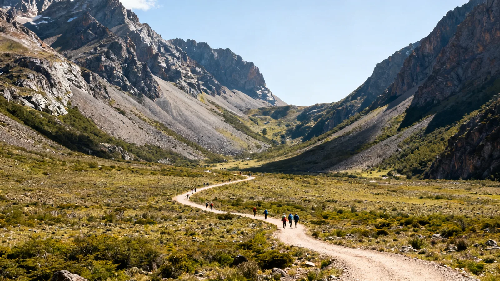 A wide patagonian mountain valley with a winding trail and tiny hikers