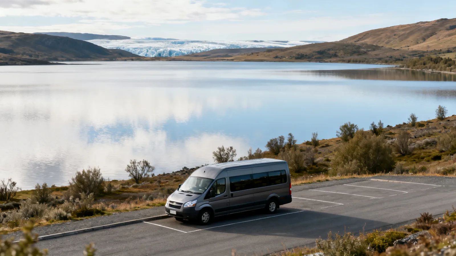 An unbranded minibus at a rest area beside a broad southern glacial lake